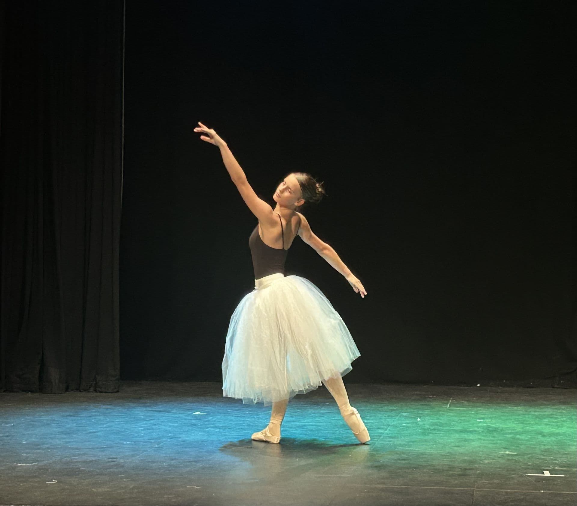 Ballet student in a white tutu on stage