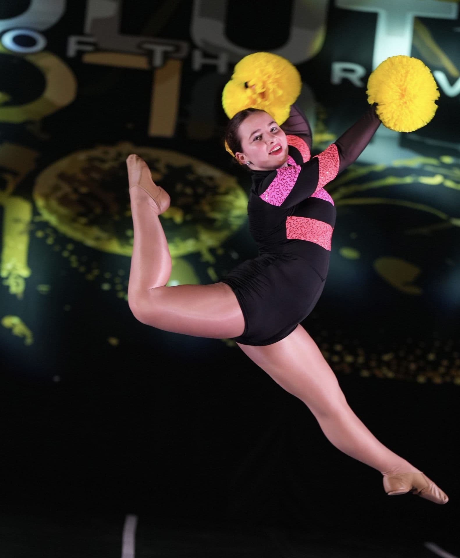 Pom dancer leaping with yellow pom-poms