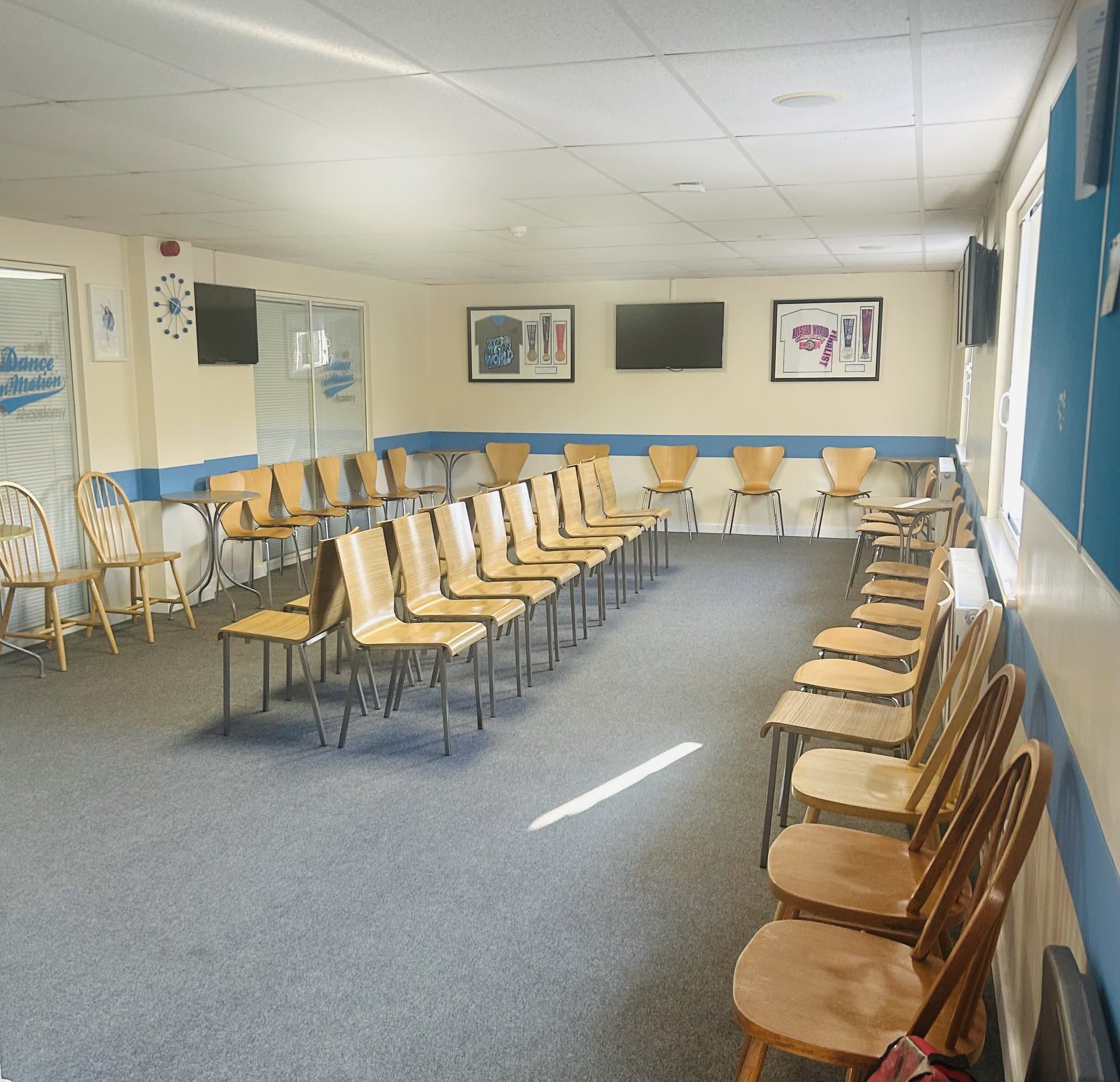 Waiting area at Dance in Motion Academy with seating and live viewing screens